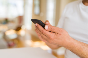 Close up of middle age man hands using smartphone at home