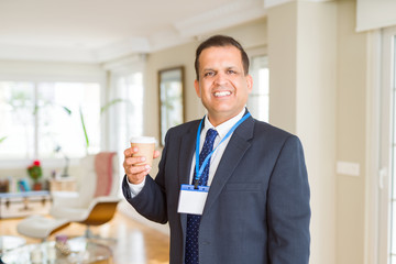 Middle age business man drinking a cup of coffee wearing identification card