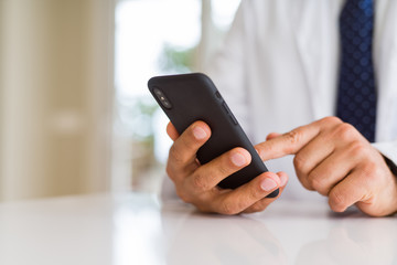 Close up middle age doctor man hands using smartphone