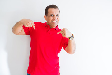 Middle age man wearing red t-shirt over white wall looking confident with smile on face, pointing oneself with fingers proud and happy.