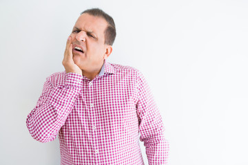 Middle age man wearing business shirt over white wall touching mouth with hand with painful expression because of toothache or dental illness on teeth. Dentist concept.