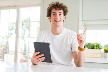 Young man using touchpad tablet very happy pointing with hand and finger to the side