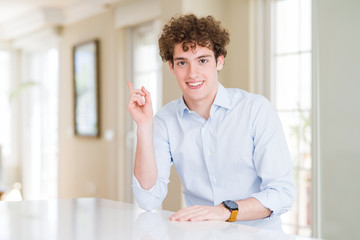 Young business man with curly read head with a big smile on face, pointing with hand finger to the side looking at the camera.