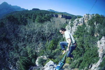 A man is walking along a stretched sling. Highline in the mountains. Man catches balance....