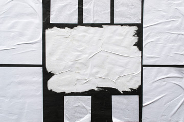 Several sheets of white paper pasted on a black wall.