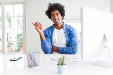 African American man working using computer very happy pointing with hand and finger to the side