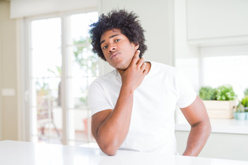 Fototapeta na wymiar Young african american man wearing casual white t-shirt sitting at home Touching painful neck, sore throat for flu, clod and infection