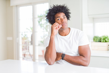 Fototapeta na wymiar Young african american man wearing casual white t-shirt sitting at home mouth and lips shut as zip with fingers. Secret and silent, taboo talking