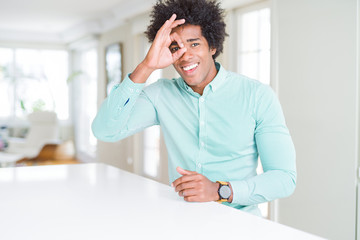 Fototapeta premium African American business man wearing elegant shirt doing ok gesture with hand smiling, eye looking through fingers with happy face.