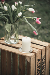 Kerze und Blumen auf Holzkiste