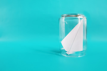 Freedom concept. Paper plane in jar. Blue background. Copy space for text