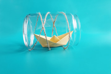 Freedom, release and dreams art concept. Paper golden ship in jar. Isolated on blue background. Copy space