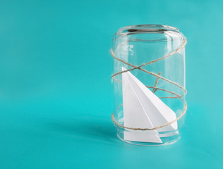 Introvert, restrictions and loneliness concept. Paper plane in jar. Isolated on blue background....