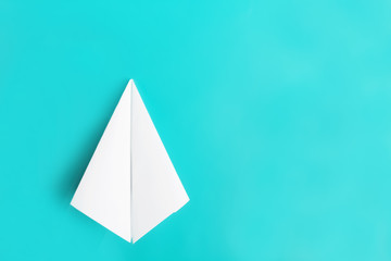 Fototapeta premium Top view of white paper plane on pastel blue color background