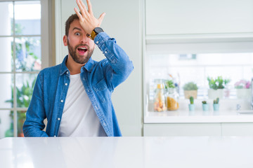 Handsome man at home surprised with hand on head for mistake, remember error. Forgot, bad memory...