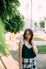 Brunette girl in a summer day in the city wearing round sunglasses