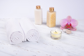 Fototapeta na wymiar Spa, beauty and wellness products: cream, sea salt, towels, decorated with orchid flower and candle with copy space. 