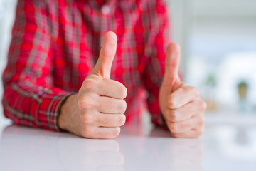 Close up of hands man doing thumbs up gesture over white table