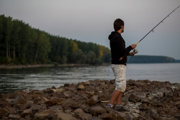 Fototapeta na wymiar Fisherman. Young man fishing on the river.
