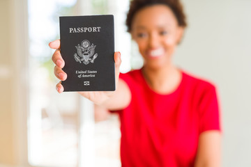 Young african american woman holding passport of United States of American with a happy face standing and smiling with a confident smile showing teeth - Powered by Adobe