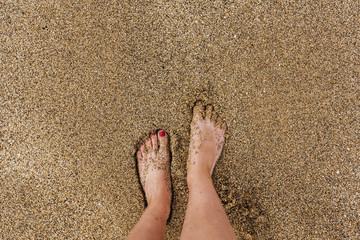 Sea foam, waves and naked feet on a sand beach. Holidays, relax, summer background. pebble background