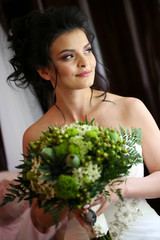 Beautiful brunette bride posing with bouquet of flowers in hands