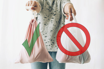Ban single use plastic, stop sign. Choose plastic free. Zero Waste shopping concept. Woman holding in one hand groceries in reusable eco bag and in other vegetables in plastic polyethylene bag