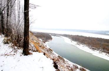 Winter landscape, the bed of a wide river and the bank in the snow, view from the top