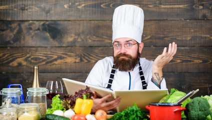 Culinary arts. Recipe to cook healthy food. Experienced chef cooking excellent dish. This recipe is just perfect. Vegetarian recipe. Man bearded hipster read book recipe near table fresh vegetables