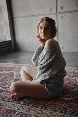 Beautiful girl sitting on the background of a concrete wall