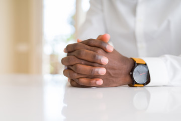 Close up of crossed hands of african man over table