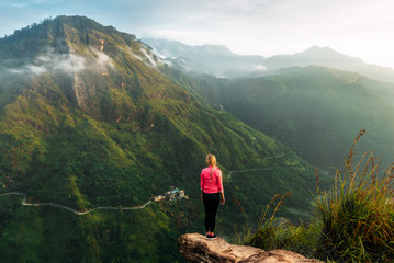 Girl meets sunrise in the mountains. Girl traveling to Sri Lanka. Mountain sports. Athlete happy finish. Mountain tourism. Walking tour. The journey to the mountains. Man on the edge of the mountain