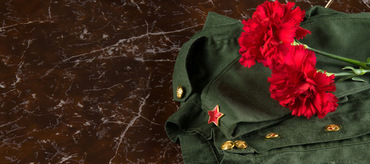 against the background of the monument, with a place for the inscription immortal regiment, two red carnations on the military uniform and cap