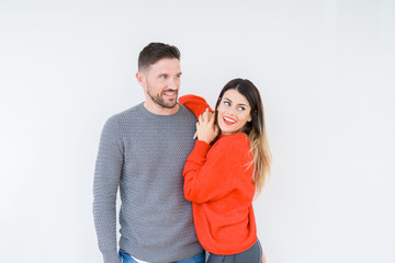 Young beautiful couple togheter over isolated background looking away to side with smile on face, natural expression. Laughing confident.