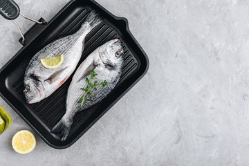 Fresh raw dorado fish with spices. Ingredients for cooking in cast iron grill pan.