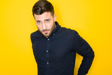 Young handsome man possing and modeling over yellow isolated background