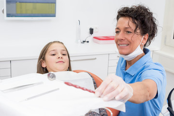 Zahnärztin nimmt ein Instrument zur Untersuchung der Zähne eines Kindes