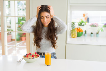 Young woman eating healthy breakfast in the morning suffering from headache desperate and stressed...