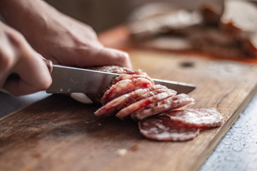 cut sausage with a knife on a wooden board