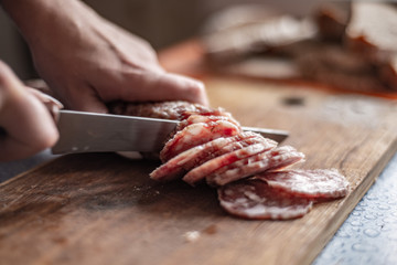 cut sausage with a knife on a wooden board