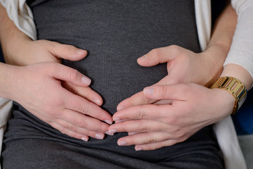 pregnant woman: male and female hands around abdomen