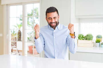 Handsome hispanic business man excited for success with arms raised celebrating victory smiling. Winner concept.