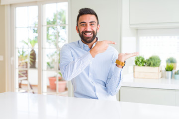 Fototapeta premium Handsome hispanic business man amazed and smiling to the camera while presenting with hand and pointing with finger.