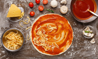 Process of pizza preparation. Unbaked pizza with grated cheese