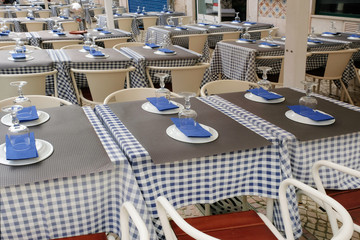 Tables in an outdoor cafe, with checkered tablecloths and blue napkins