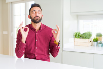 Handsome hispanic business man relax and smiling with eyes closed doing meditation gesture with fingers. Yoga concept.