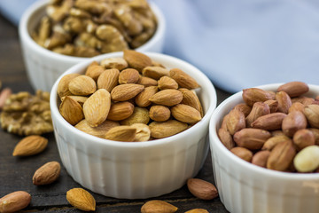 Tasty nuts arrangement in a bowl on a wooden table. Healthy food and snack, organic vegetarian food. Walnut, almond, peanut