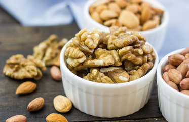 Tasty nuts arrangement in a bowl on a wooden table. Healthy food and snack, organic vegetarian food. Walnut, almond, peanut
