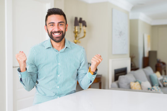 Handsome hispanic man at home celebrating surprised and amazed for success with arms raised and open eyes. Winner concept.