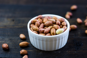 A tasty arrangement of peanuts nuts in a bowl on a wooden table. Healthy food and snack, organic vegetarian food